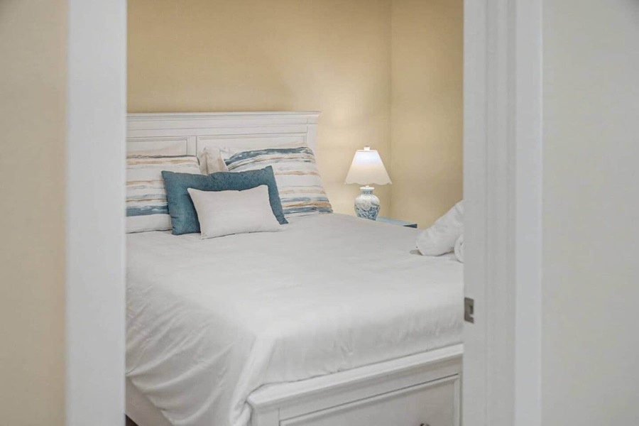 Bedroom with a white cottage-style bed dressed in lake-blue accent pillows